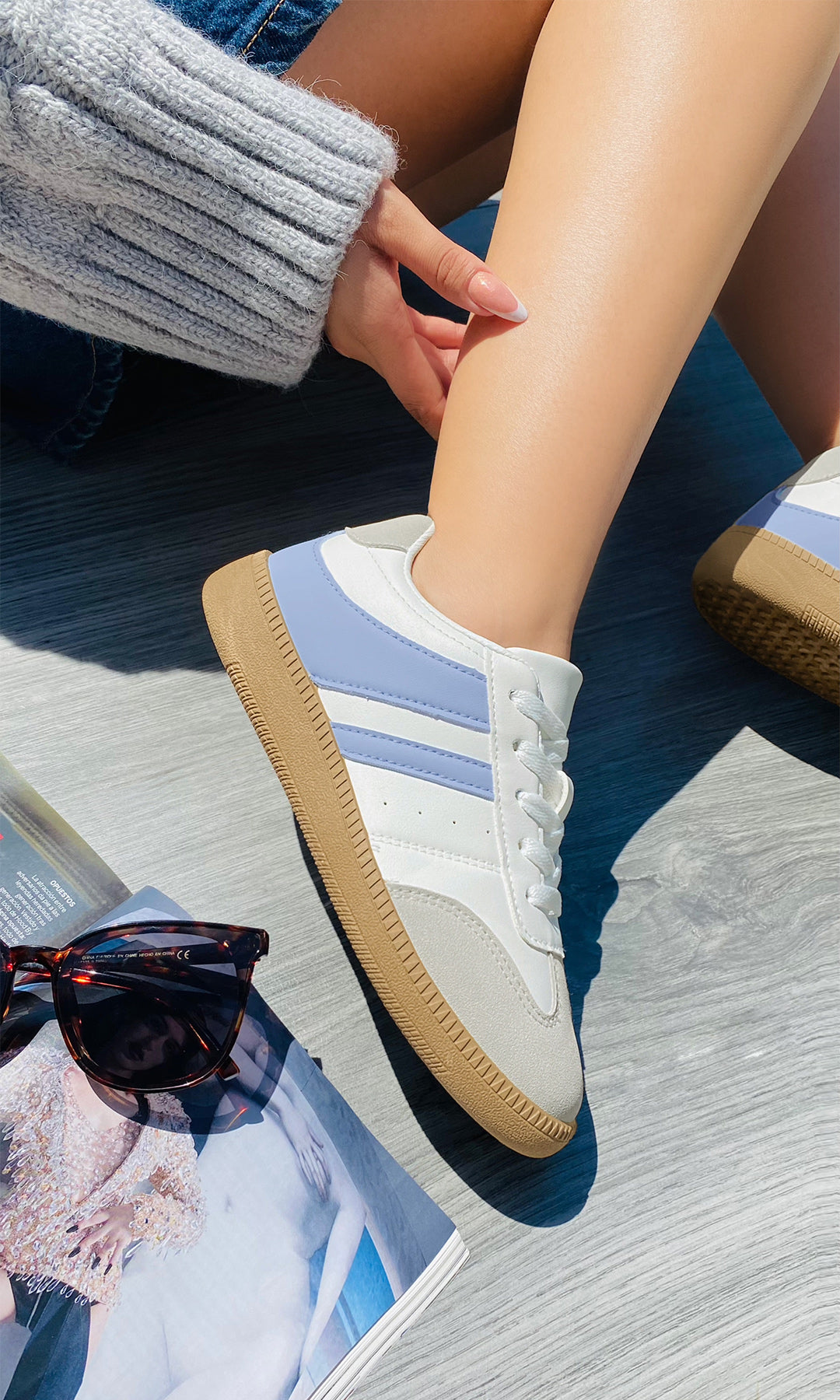 ALTHEA TENIS BLANCOS CON DETALLES AZULES MÁS SHORTS DE MEZCLILLA Y SUÉTER TEJIDO CREAN UN OUTFIT RELAJADO IDEAL PARA PASEAR